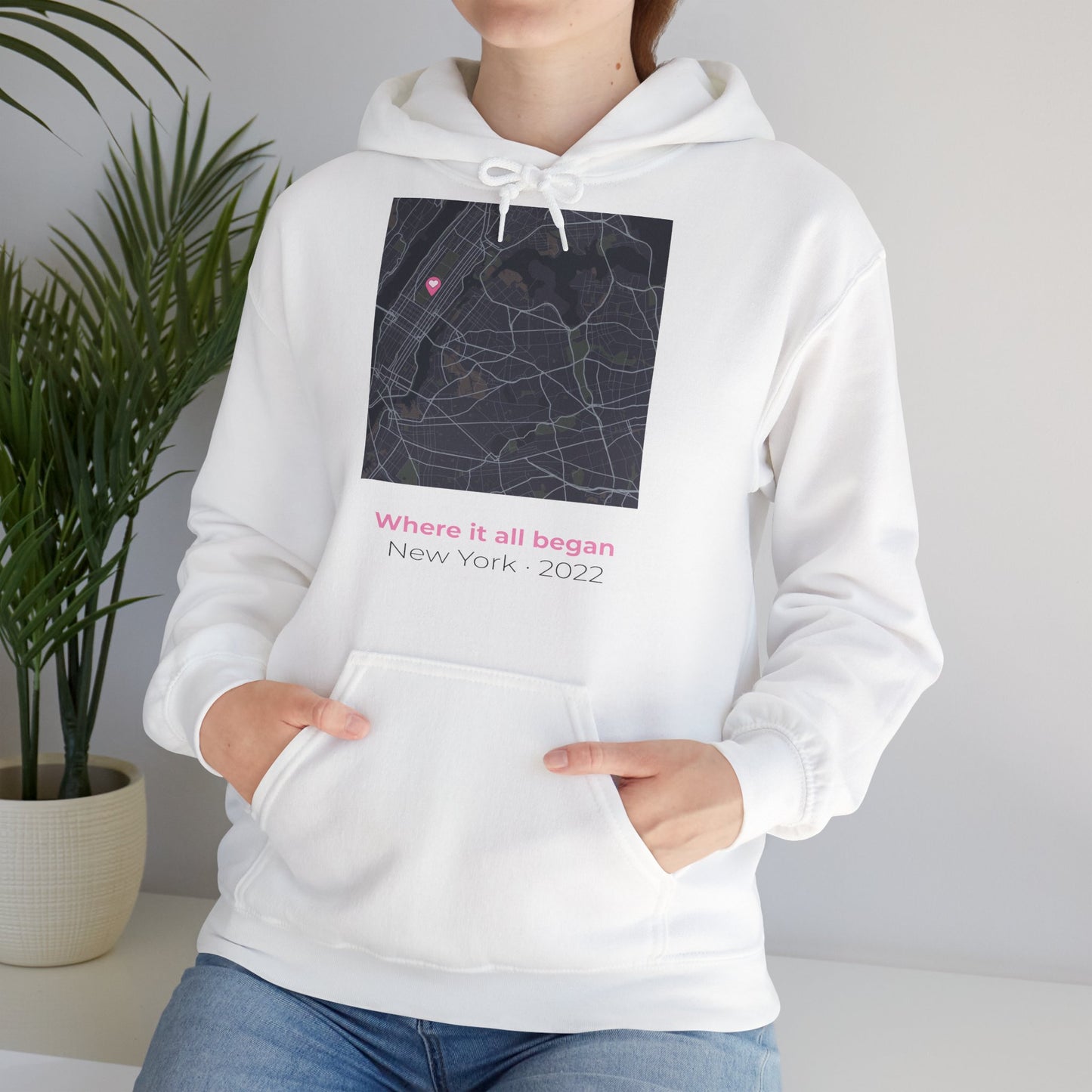 White hoodie with a map design and text, worn by a person, against a neutral background.
