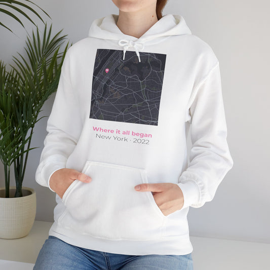 White hoodie with a map design and text, worn by a person, against a neutral background.